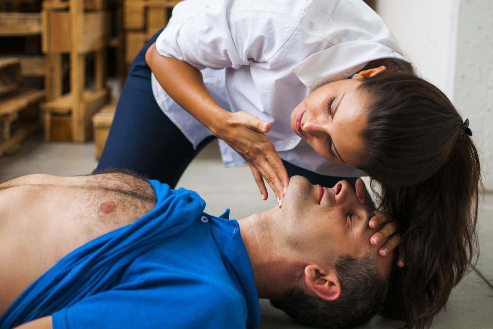 Mujer aplicando procedimiento de soporte vital básico en paciente
